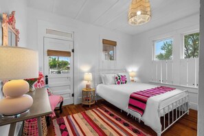 Un dormitorio con cama, lámparas de noche, una ventana y una puerta.