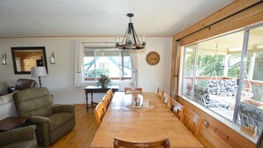 Un comedor con una mesa y sillas de madera, un candelabro y un ventanal con vistas al exterior.