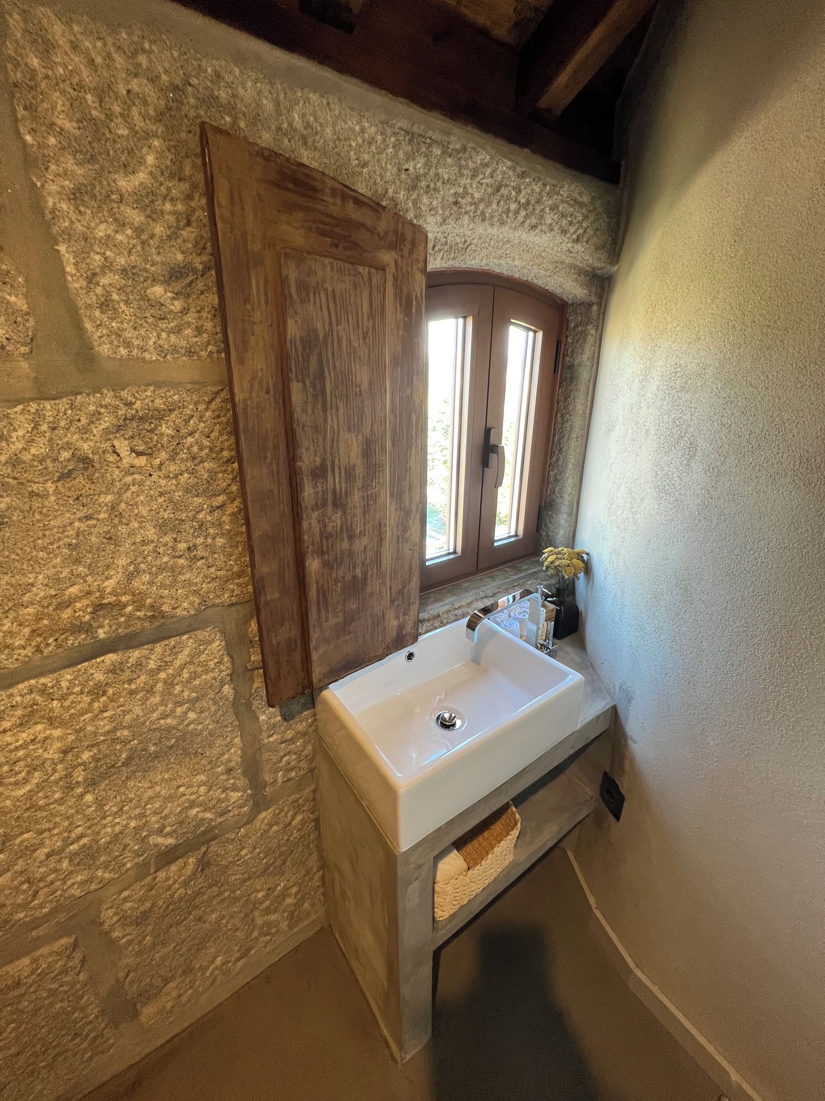 Ein Badezimmer mit Steinwand, Holztür und Fenster.