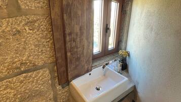 Un bagno con parete in pietra, porta in legno e una finestra.