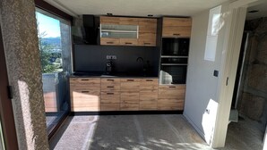 A modern kitchen with wooden cabinets, a built-in oven, and a large window offering a view of the outdoors.