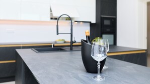 A modern kitchen with a dark countertop, a wine glass, and a bottle of champagne. - Hedera Estate, Hedera A25 (Dubrovnik)