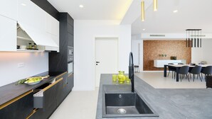 A modern kitchen with a built-in oven, a sink, and a dining area with a table and chairs. - Hedera Estate, Hedera A25 (Dubrovnik)
