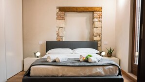 Une chambre moderne avec un grand lit, un arc en pierre sur le mur et des tables de chevet avec des lampes.