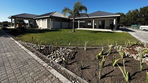 Un edificio de dos pisos con un patio cubierto y un jardín ajardinado con cactus.
