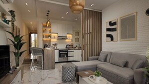 A modern living room with a grey sofa, a coffee table, and a TV. There is a kitchen in the background with white cabinets and a wooden island. - Marina Resort By Seven Seasons Hospitality (Al-Hammam)