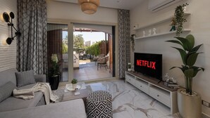 A modern living room with a grey sofa, a flat-screen TV, and a large potted plant. - Marina Resort By Seven Seasons Hospitality (Al-Hammam)