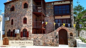 A traditional stone building with multiple windows and a balcony. - Elounda Monastiri Cretan sea View House With Pool (Agios Nikolaos)