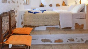 A bedroom with a bed, a chair, a nightstand, and a lamp. - Elounda Collection Villa (Agios Nikolaos)