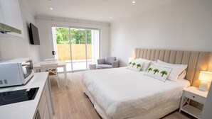 Une chambre moderne avec un grand lit, un bureau, une chaise et un téléviseur fix é au mur.