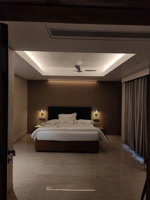 A modern hotel room with a large bed, a ceiling fan, and two wall-mounted lamps. - Sakthi Holiday's Inn (Port Blair)
