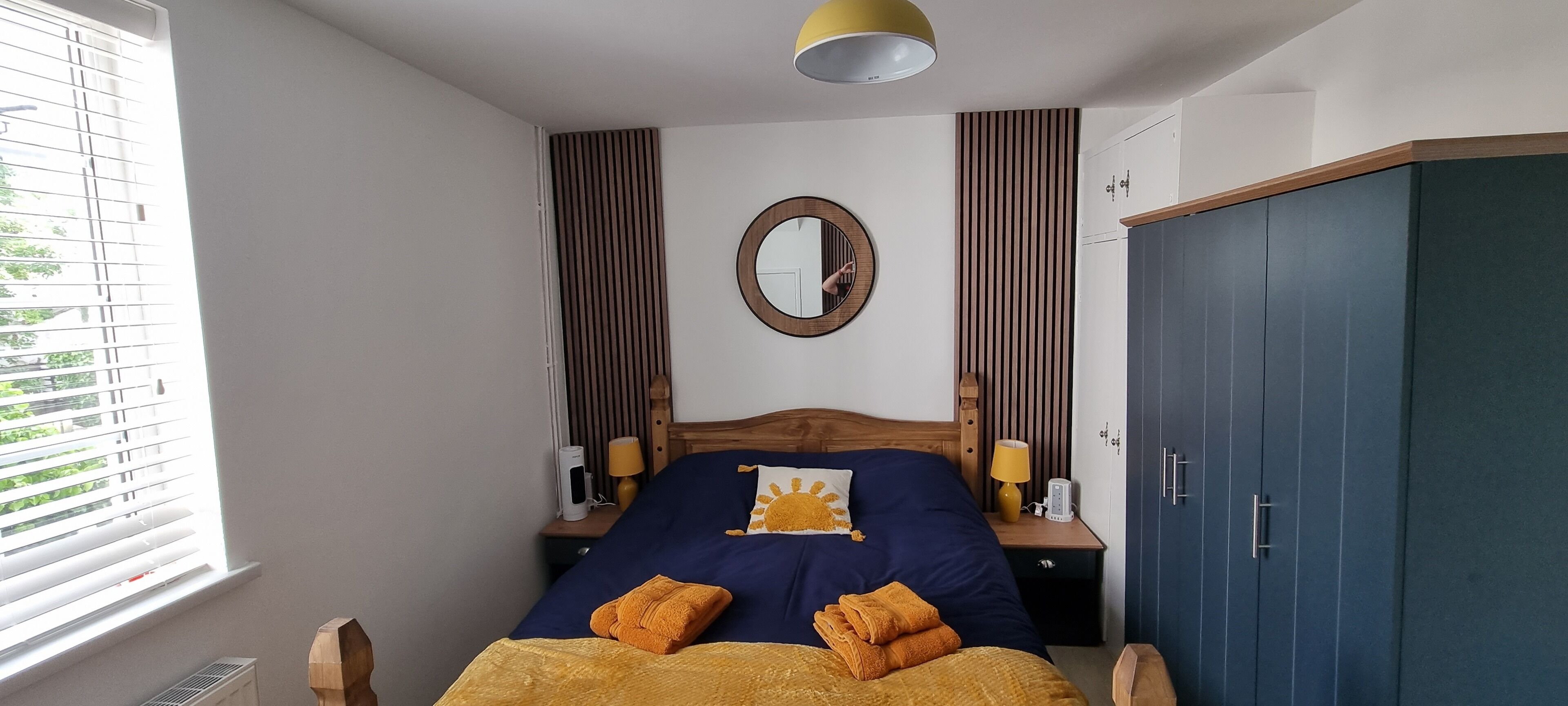 A bedroom with a bed, bedside lamps, a mirror, and a wardrobe.