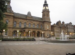 A historic building with a prominent clock tower, arched windows, and a fountain in the courtyard. - The Hideaway ll /enclosed Garden/quiet/central (Southport)