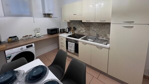 Una cocina compacta equipada con microondas, tostadora, pileta y cafetera. Incluye un comedor con mesa y sillas.