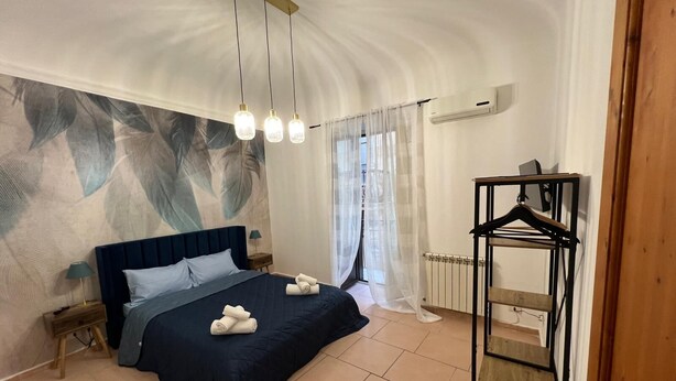 Un dormitorio con una cama grande, una lámpara colgante, un radiador y un perchero de madera.