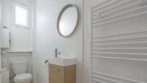 A small, modern bathroom with a toilet, sink, and mirror. - TEA&CHILL - Mimosa - Proche métro 5 (Drancy)