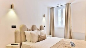 Ein ordentlich eingerichtetes Schlafzimmer mit einem Bett, Nachttischen und einem Fenster mit Vorhängen.