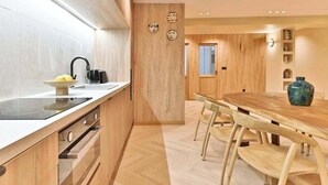 Eine moderne Küche mit weißer Arbeitsplatte, Holzschränken und einem Essbereich mit Holztisch und -stühlen.