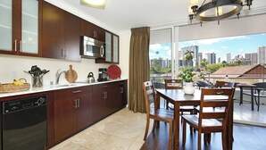 A modern kitchen with dark wood cabinets, a dishwasher, and a dining area with a table and chairs.