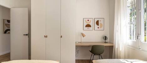 A bedroom with a bed, a desk, and a wardrobe.