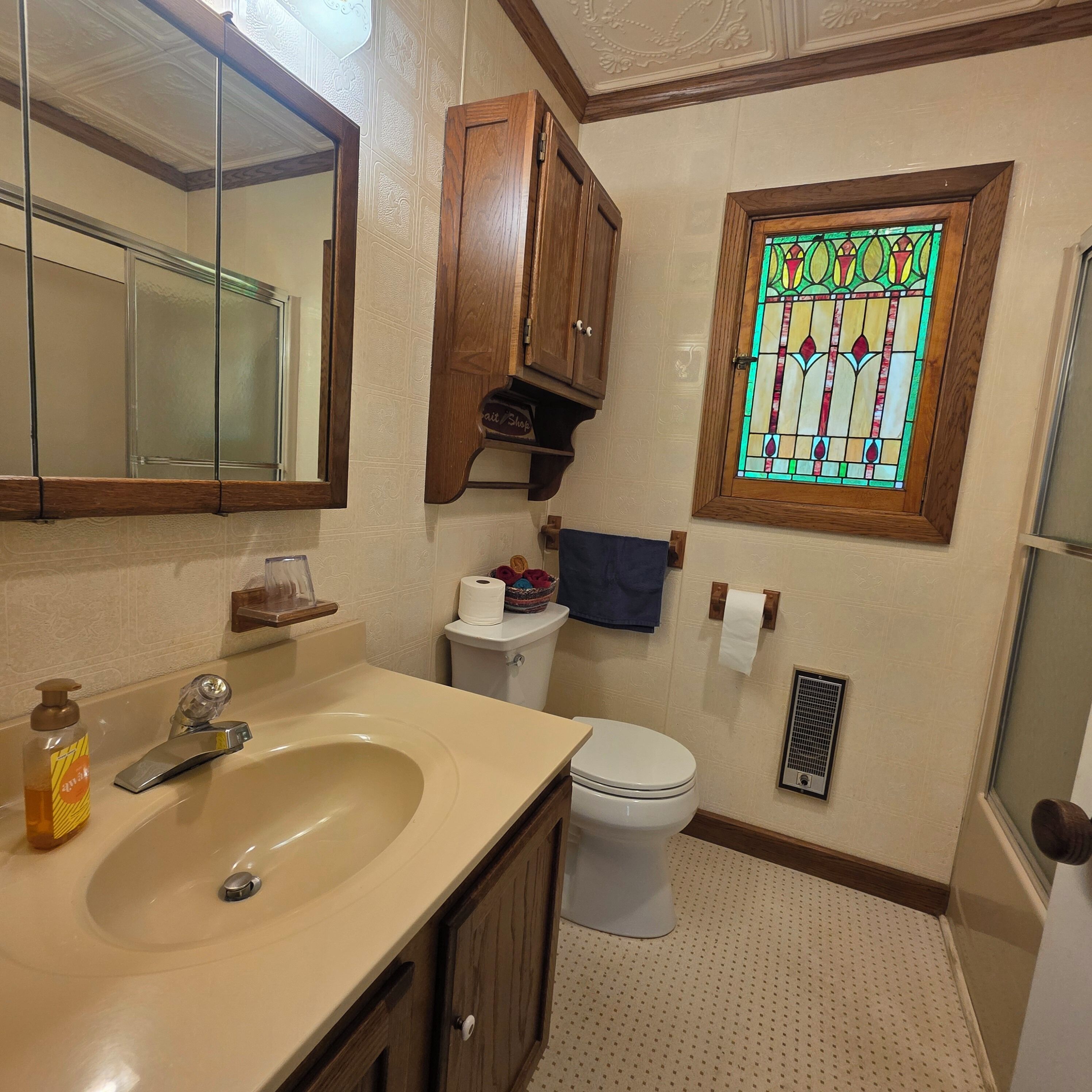 A bathroom with a sink, toilet, and a stained glass window.
