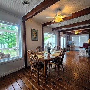 A dining area with wooden flooring, a table set for four, and a ceiling fan.
