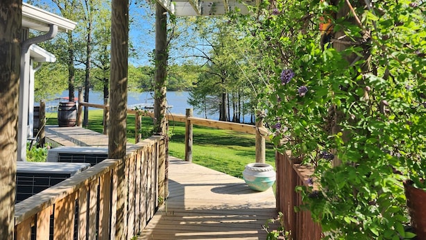 Eine Holzterrasse führt zu einem Haus mit einem Pergola-Eingang.