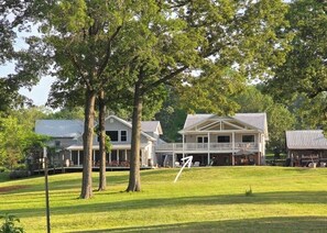 A large house with a front porch, a covered deck, and a well-maintained lawn.