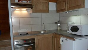 A compact kitchen with wooden cabinets, a built-in oven, a microwave, and a sink. - 300m from ski slopes, 2nd floor, balcony, parking, tv, ski locker, 22m², Valloire (Valloire)