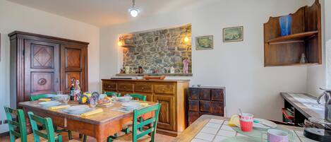 A dining area with a wooden table, green chairs, and a stone wall above.