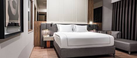A modern bedroom with a large bed, a nightstand, a lamp, and a mirror.