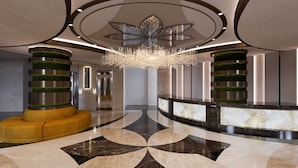 A modern lobby with a central chandelier, a reception desk, and a unique floor pattern. - Renex Hotels (Antalya)