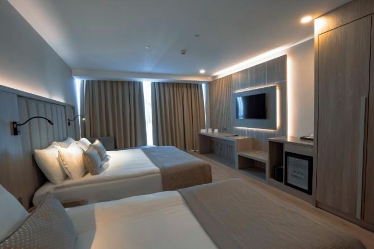 A hotel room with two beds, a TV, a desk, and a wardrobe.