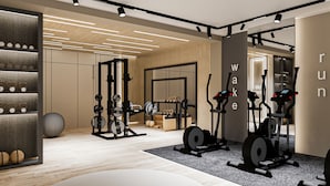 A modern gym with various exercise equipment, a weight rack, and a wall with the word "wake" partially visible. - Renex Hotels (Antalya)
