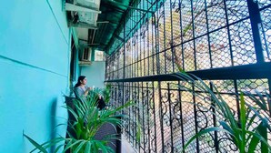 A balcony with a metal fence, potted plants, and a person standing by the railing. - Charming 3 Bed 2 Bath in Bandra West with Balcony
 (Mumbai)