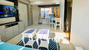 A modern living room with a flat-screen TV, a dining area with a table and chairs, and a kitchen with cabinets and a countertop. - Charming 3 Bed 2 Bath in Bandra West with Balcony
 (Mumbai)