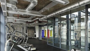 Una palestra moderna con attrezzi, ampie finestre e condotti a vista.