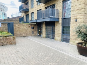 A modern building with a brick facade, large windows, and a gated entrance.