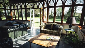 Una habitación amplia con un ventanal grande, un sofá de cuero, un sillón a rayas y una mesa de centro de madera.