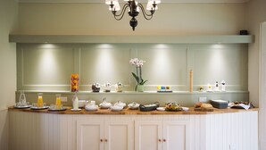 Una cocina con isla integrada, muebles blancos y una lámpara colgante.