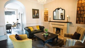 Una sala de estar bien iluminada con chimenea, una mesa de centro y diversas opciones de asientos, incluyendo un sofá y sillones.