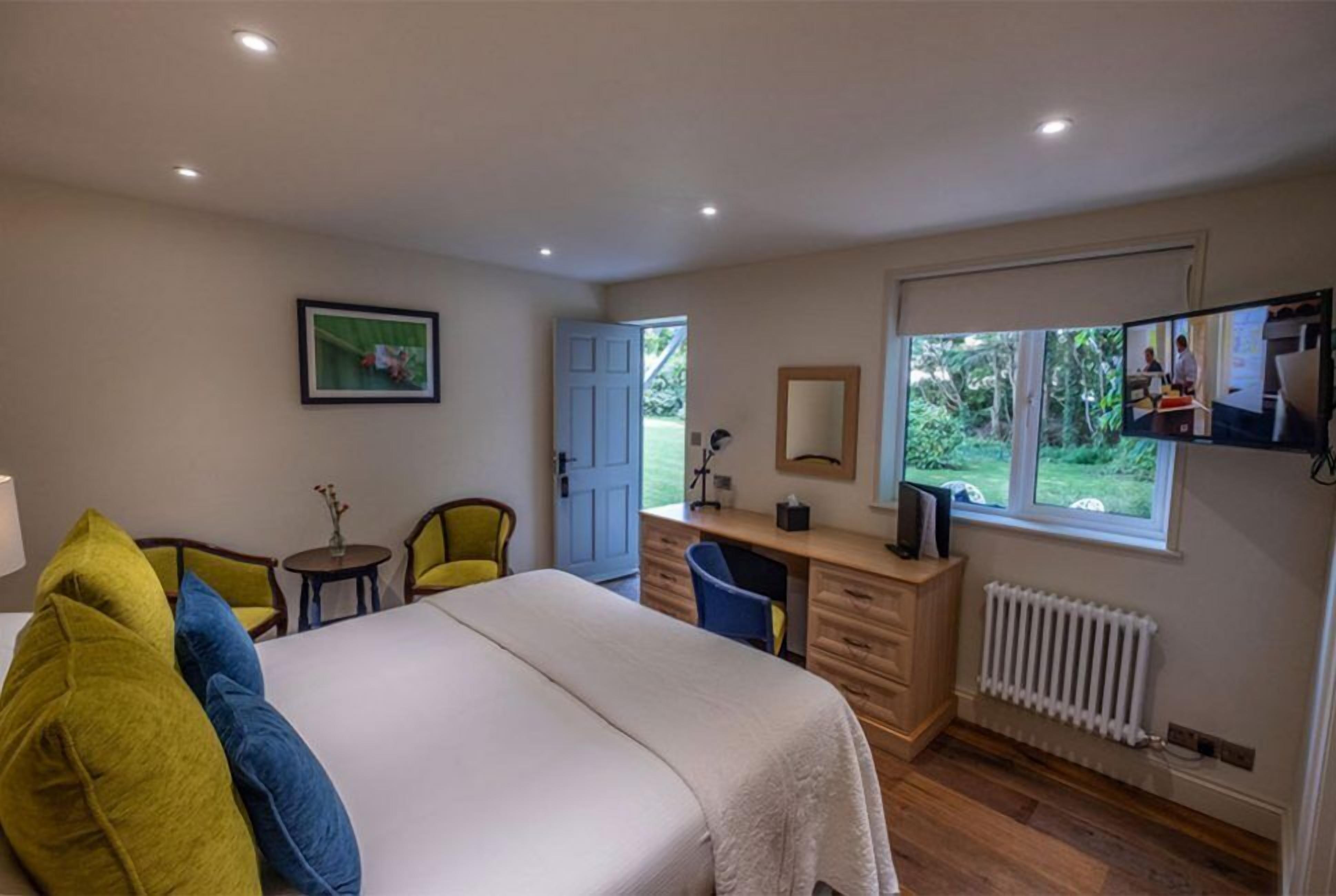 Une chambre à coucher comprenant un lit, un bureau, une chaise, un radiateur et une fenêtre donnant sur un paysage verdoyant.