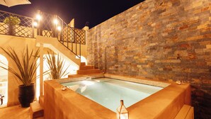 Une piscine avec un mur en pierre et des marches menant à un balcon.