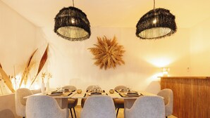 Un espace repas comprenant une table rectangulaire, six chaises et deux luminaires suspendus.