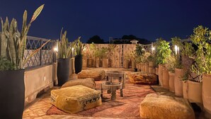 Une terrasse sur le toit agrémentée de plantes en pot, dotée de sièges extérieurs et offrant une vue sur le ciel nocturne.