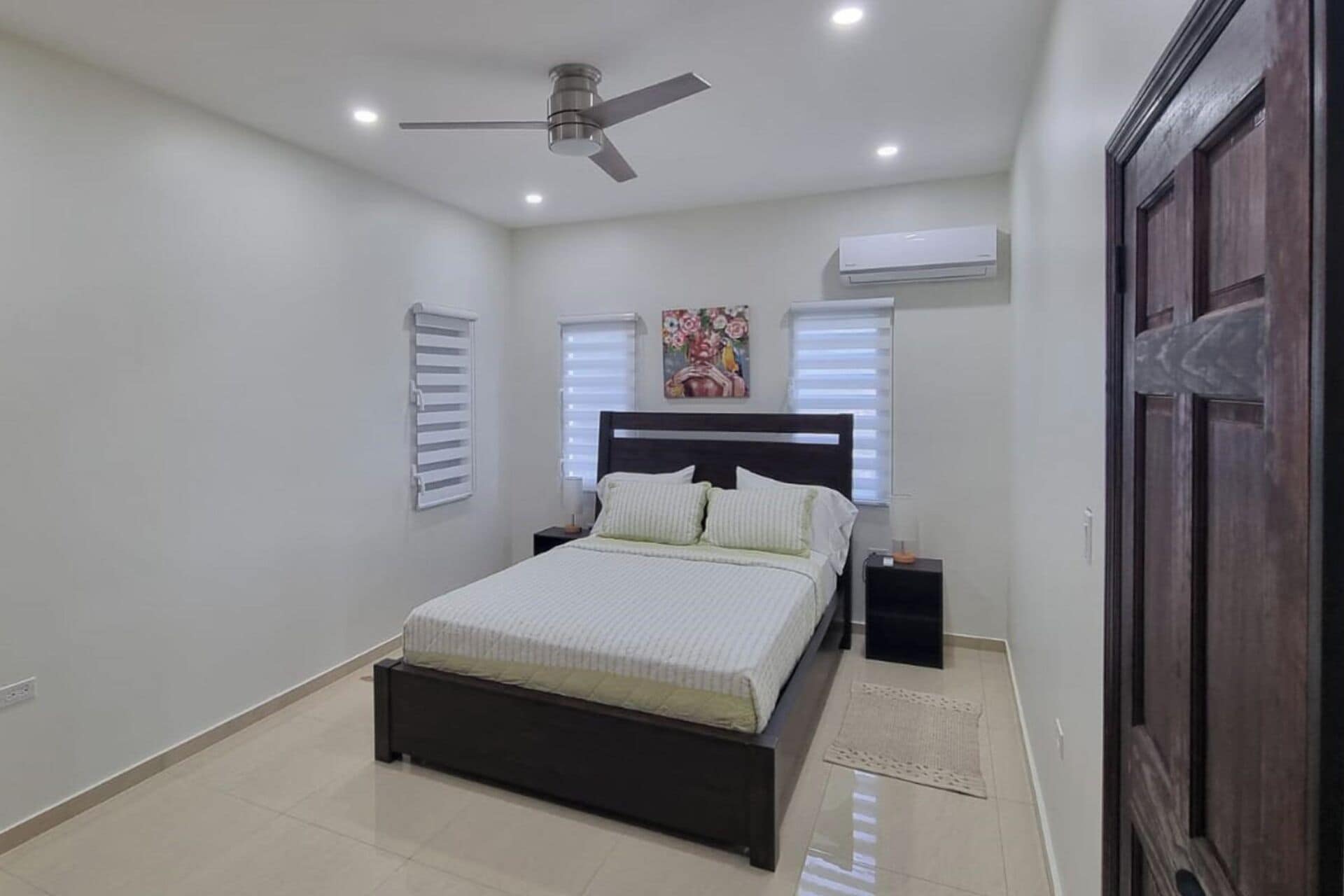 Ein Schlafzimmer mit Bett, Nachttischen, Deckenventilator und Klimaanlage.