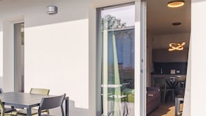 A modern kitchen with a unique light fixture, a dining area with a table and chairs, and a sliding glass door leading to a balcony. - Rosa dei Venti Ovest (Padenghe sul Garda)
