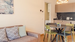 A modern living room with a sofa, a dining table with chairs, and a kitchen area with cabinets and appliances. - Rosa dei Venti Ovest (Padenghe sul Garda)