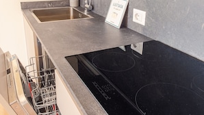 A modern kitchen with a black stovetop, stainless steel sink, and a built-in dishwasher. - Rosa dei Venti Ovest (Padenghe sul Garda)
