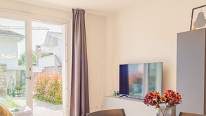 A modern living room with a dining table, chairs, a sofa, and a TV on a stand. - Rosa dei Venti Est in Padenghe sul Garda (Padenghe sul Garda)